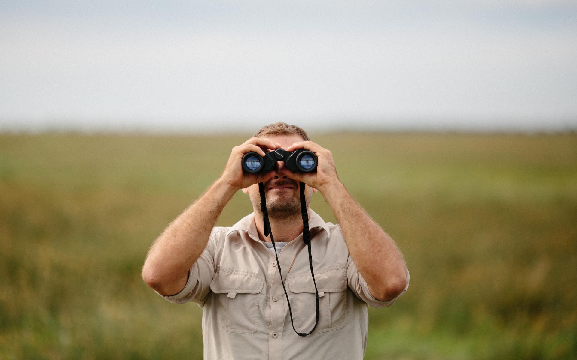 A man on safari using a pair of binoculars