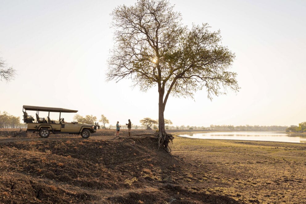 A safari traveller and guide enjoying a coffee break at sunrise in South Luangwa National Park.