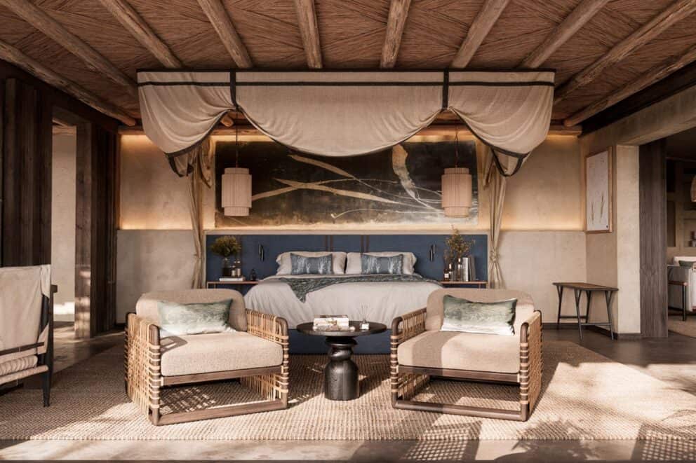 Interior view of the luxury suite, featuring a king-sized bed and comfortable armchairs at Sandringham Shisaka Camp, South Africa.