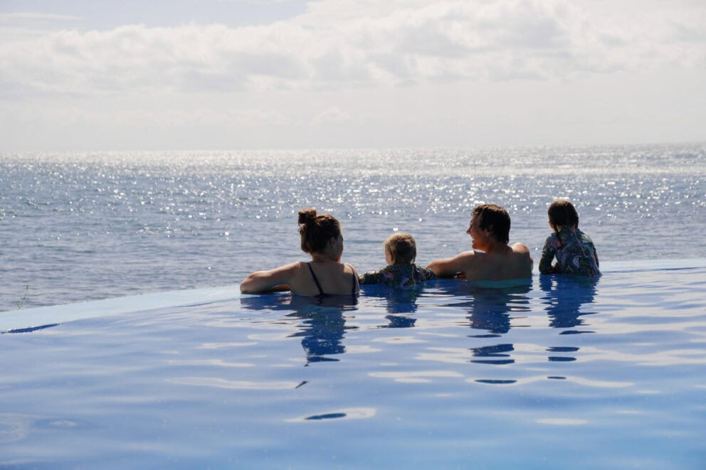 A family relaxing at the infinity pools edge overlooking Lake Malawi at Blue Zebra Island Lodge, Malawi.
