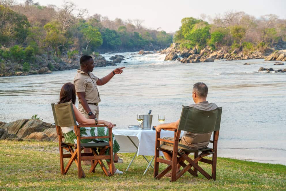 A couple having a scenic sundowner along the riverbank in the Majete Wildlife Reserve, Malawi