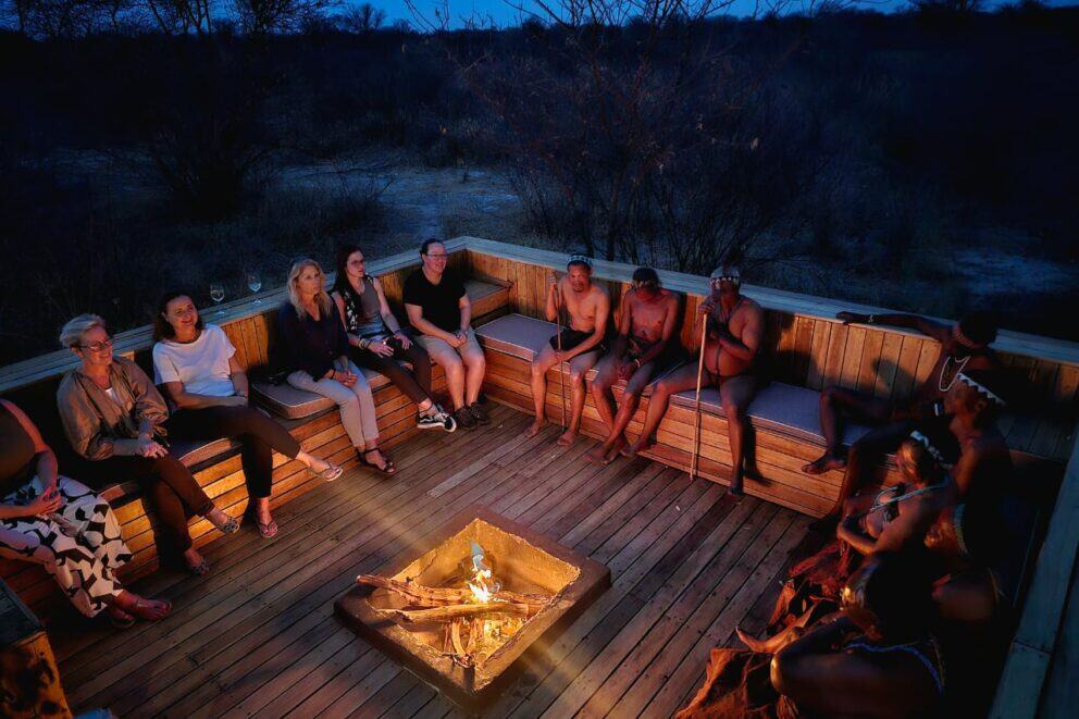 Guests and bushmen sitting around a boma fire at Feline Fields Lodge in Okavango Delta, Botswana