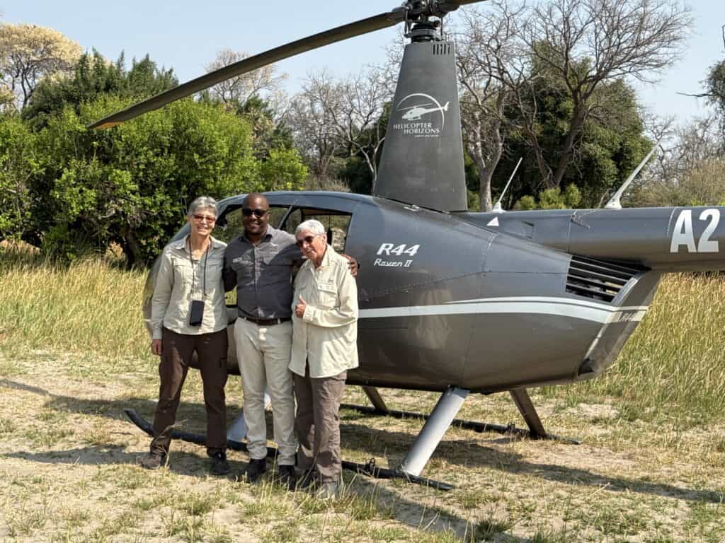 Tourists standing next to helicopter at Xugana Island Lodge, Botswana.