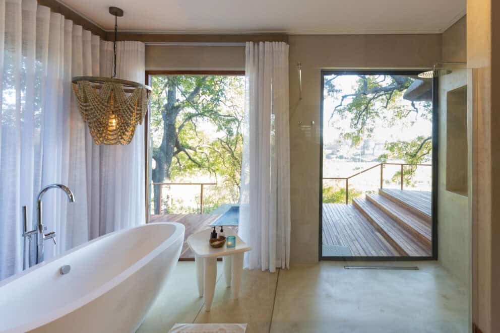 A luxury bathroom at Dulini River, South Africa, featuring a freestanding bath overlooking the river.