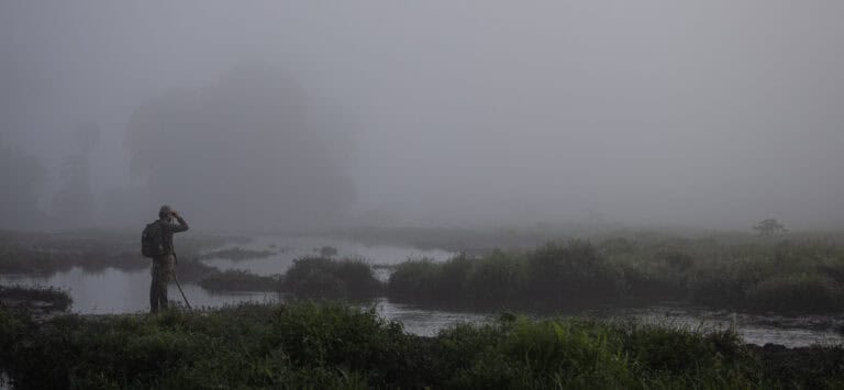 A tourist standing in the mist of the rainforest.