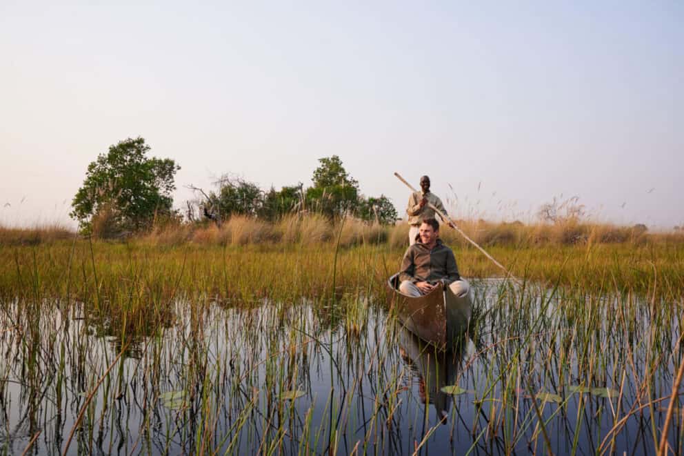 A traditional mokoro boat drifting along the papyrus-lined waterways of the Khwai River at Sediba Sa Rona, Botswana.