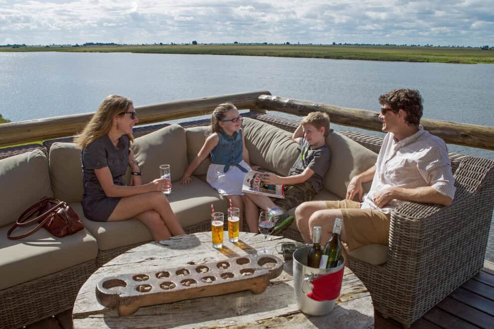 A family sitting on comfy seating enjoying some beverages while overlooking the Chobe River at Chobe Game Lodge, Botswana.
