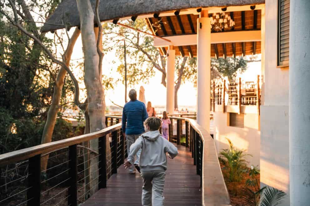 A family walking on an elevated wooden walkway at Chobe Safari Lodge, Botswana.