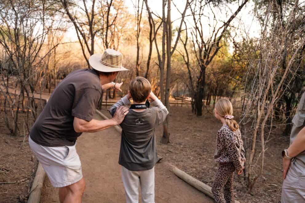 A father and kids on a nature walk observing wildlife in the distance at Chobe Safari Lodge, Botswana.