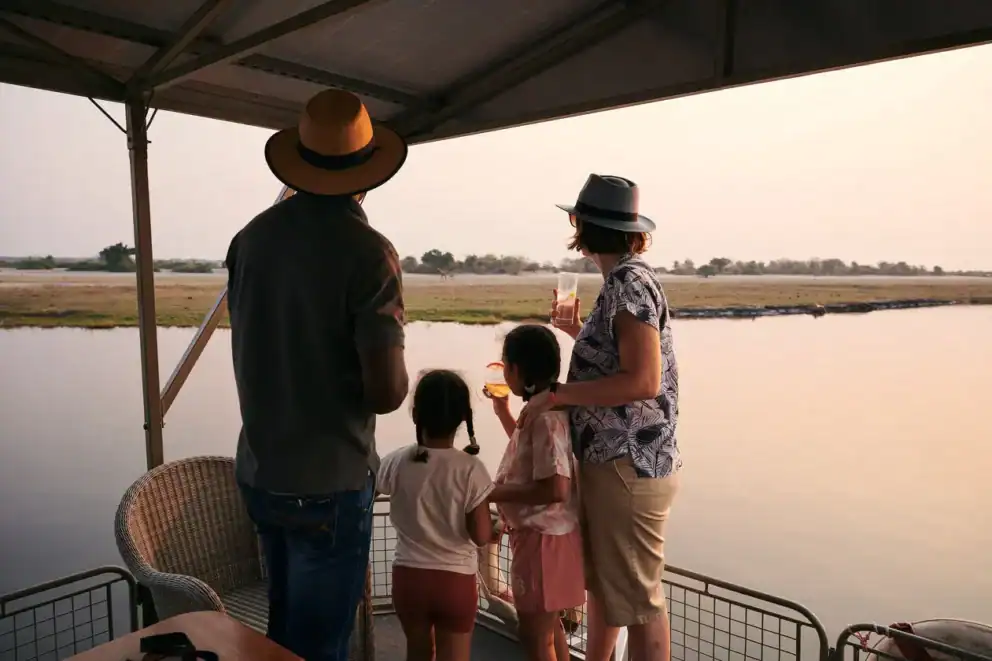 A family on a sunset boat cruise on the Chobe River at Chobe Game Lodge, Botswana.