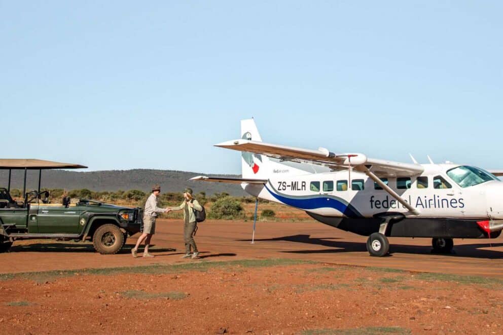 A FedAir plane parked on a runway alongside a safari vehicle.