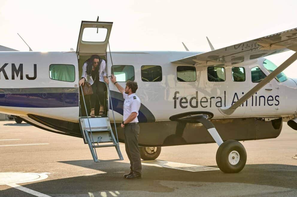 A FedAir pilot assisting a guest existing a plane.