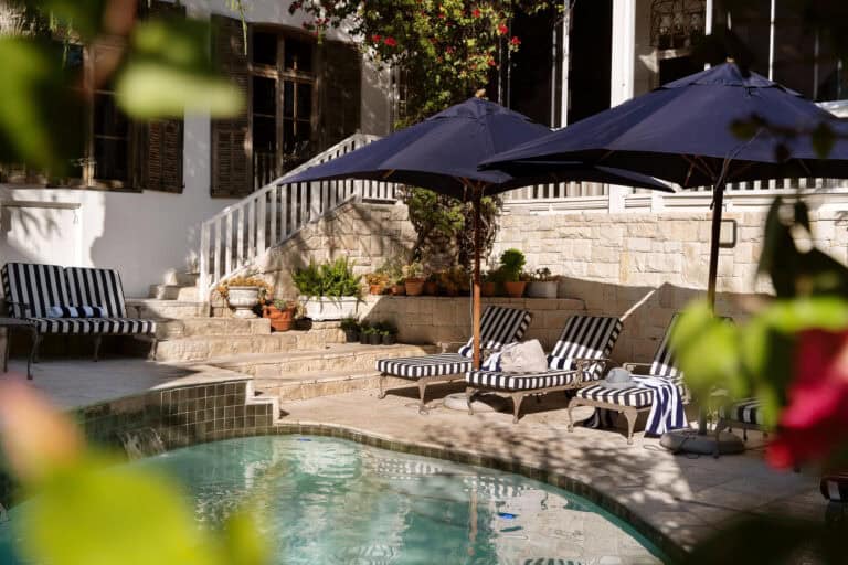 View of the pool, featuring cushioned loungers under umbrellas at Blackheath Lodge, South Africa.