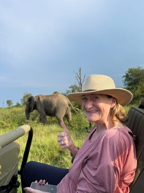 A tourist in an open-top safari vehicle on a game drive observing an elephant in the Timbavati Private Nature Reserve, South Africa.