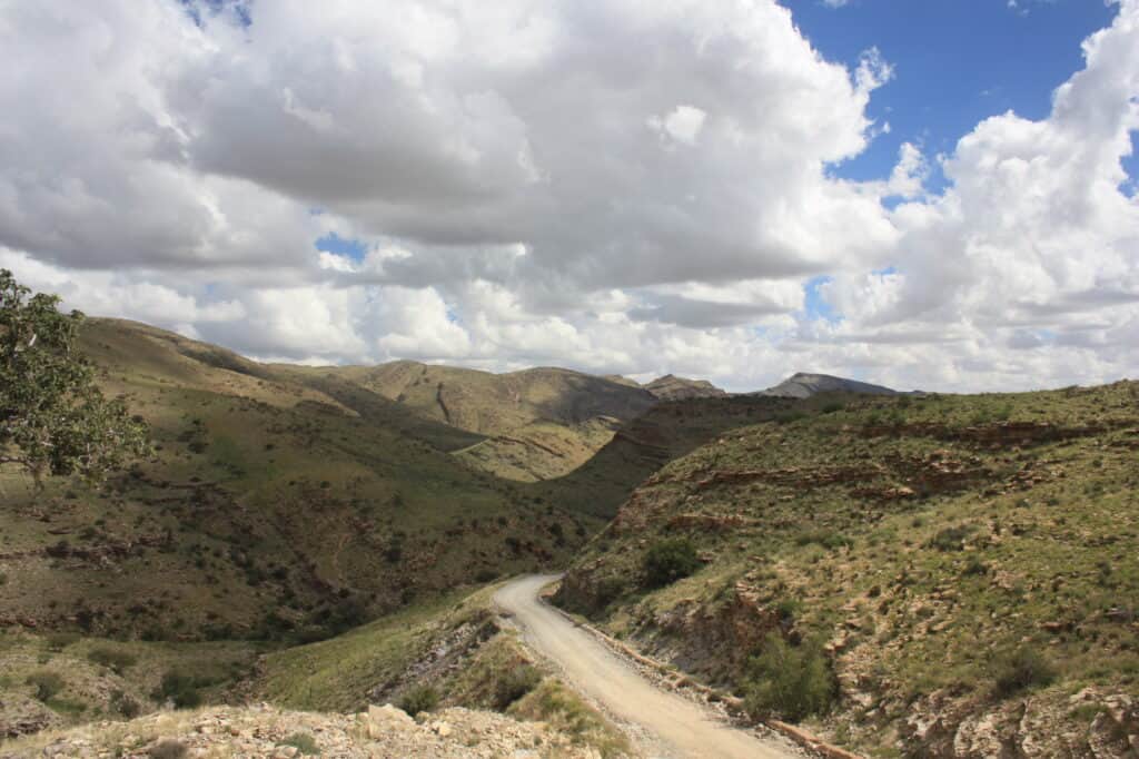 Breataking views winding gravel road surrounded by lush green rolling hills in Namibia.