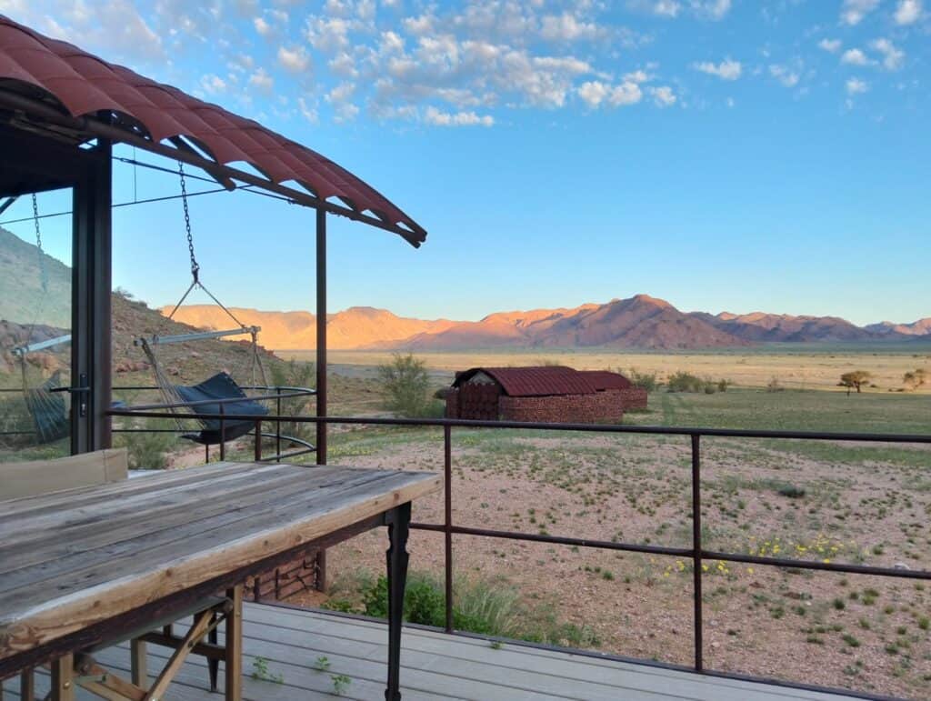 View of the dry, green landscape and rolling hills in the Namib Tsaris Conservancy at Camp Sossus, Namibia.
