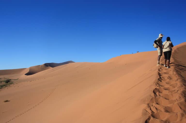 A couple walking on a dune ridge in Sossusvlei, Namibia.