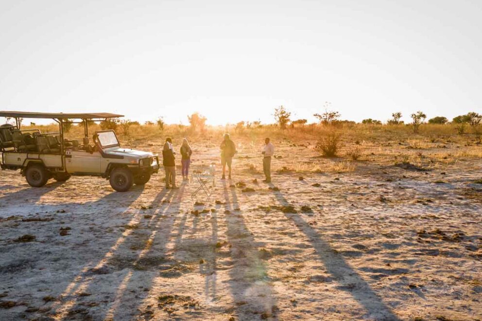 Guests enjoying a morning coffee break beside their safari vehicle, with a rustic coffee station set up in the bush near Hideaways Mankwe Tented Retreat, Botswana.